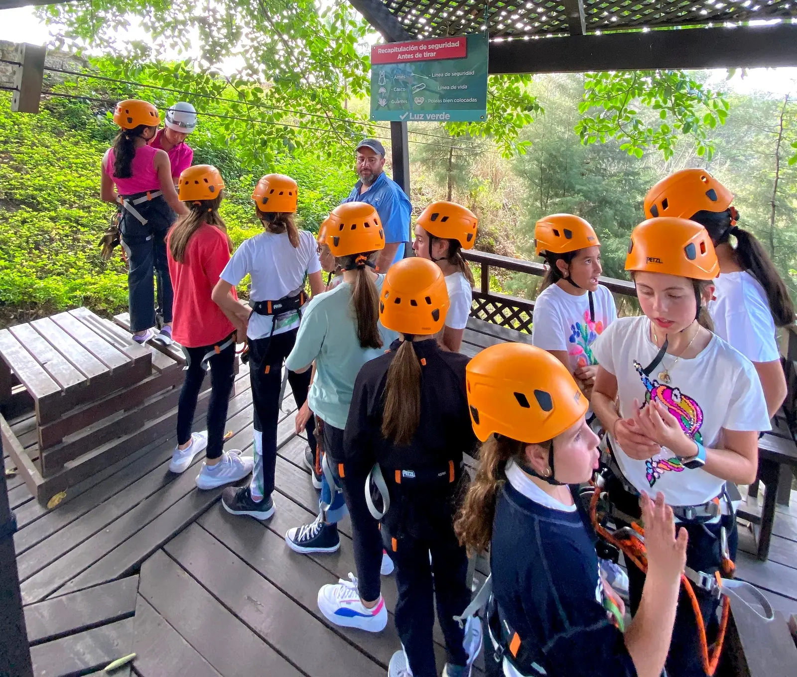 Grupo con cascos naranja y arneses en la estación del canopy, listo para volar