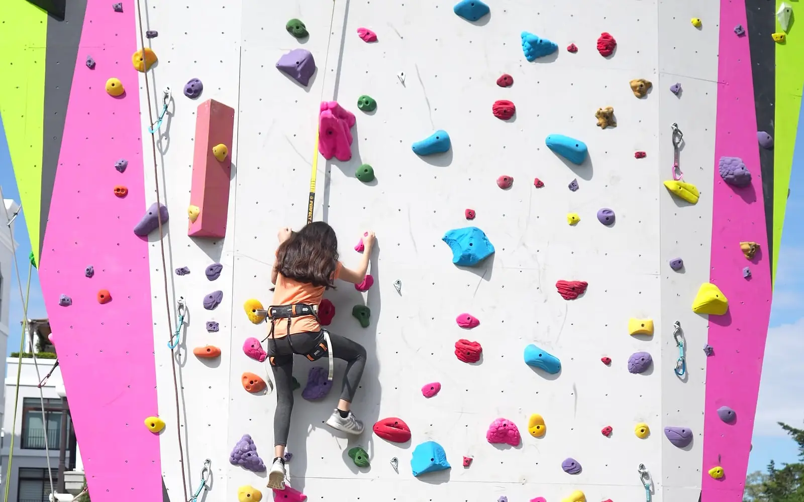 Escaladora subiendo la pared rosada de El Muro, en Cayalá